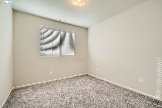 carpeted empty room with a textured ceiling