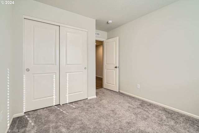 unfurnished bedroom featuring light colored carpet and a closet