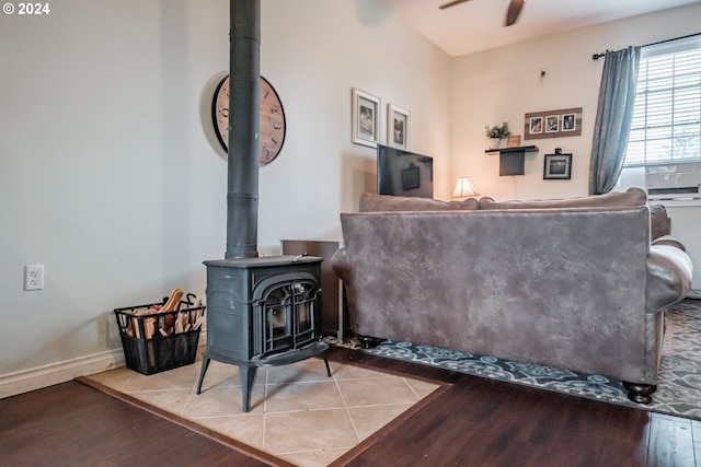 living room with a wood stove, light wood-type flooring, and ceiling fan