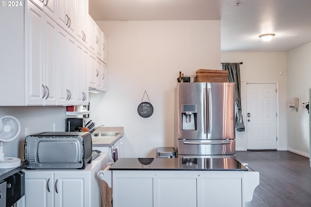 kitchen with stainless steel fridge, white cabinets, and dark hardwood / wood-style flooring