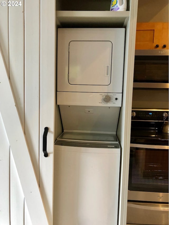 clothes washing area featuring stacked washer and clothes dryer