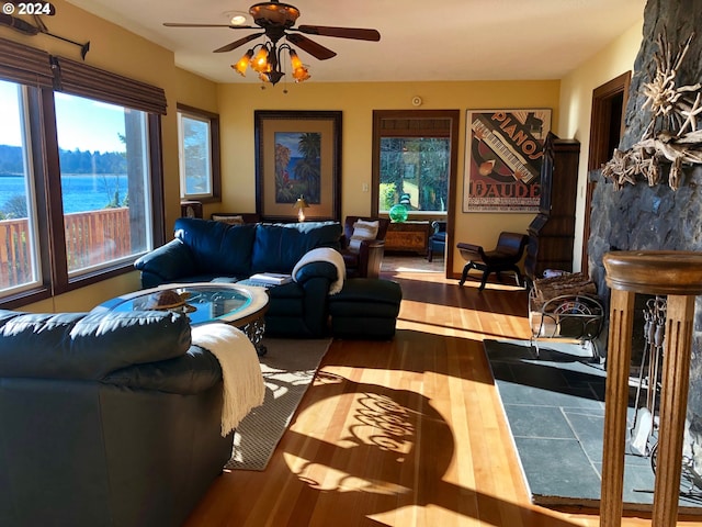 living room featuring hardwood / wood-style flooring, a water view, a wealth of natural light, and ceiling fan