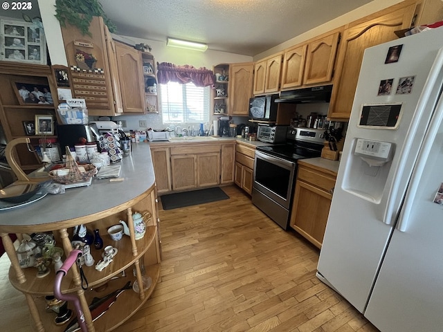 kitchen with sink, stainless steel range with electric stovetop, white refrigerator with ice dispenser, light hardwood / wood-style floors, and a textured ceiling