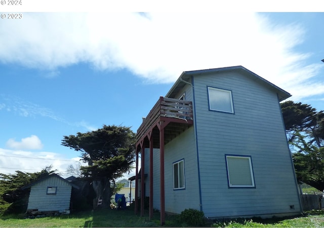 view of side of property featuring a balcony and a lawn