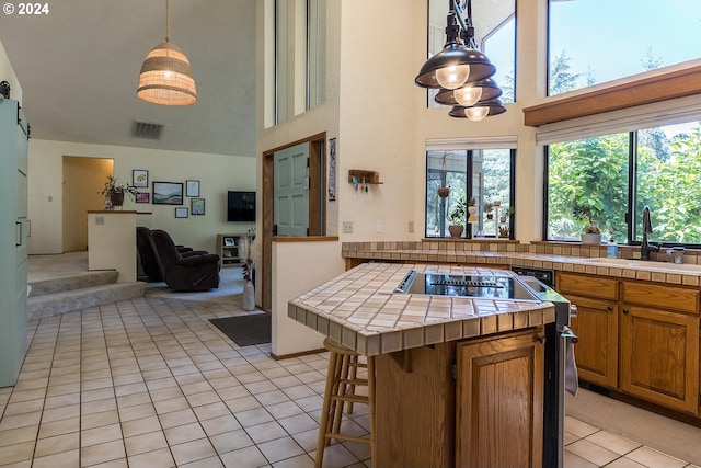 kitchen featuring light tile patterned floors, open floor plan, a sink, and tile counters