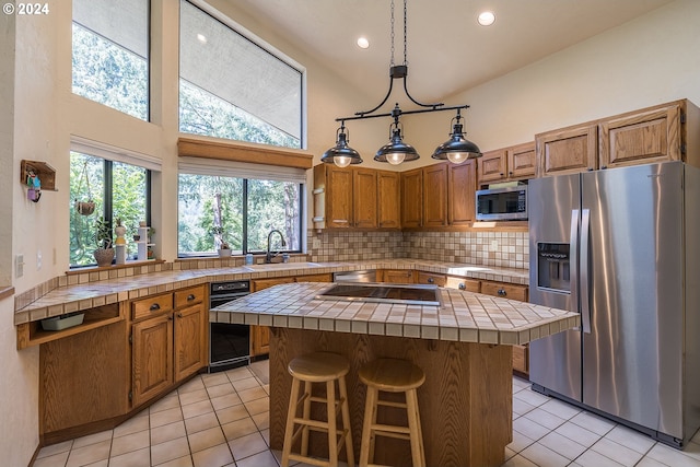 kitchen featuring appliances with stainless steel finishes, a sink, tile counters, and decorative backsplash