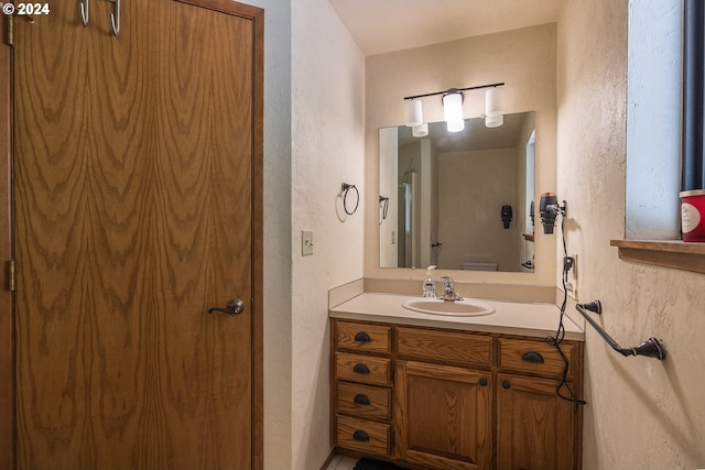 bathroom with a textured wall and vanity