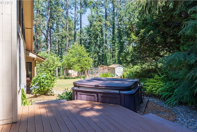 wooden terrace featuring a storage unit, a covered hot tub, and an outbuilding