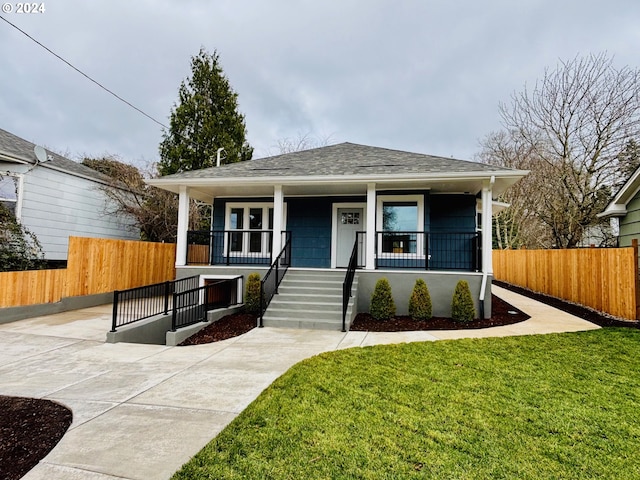 bungalow featuring covered porch and a front yard