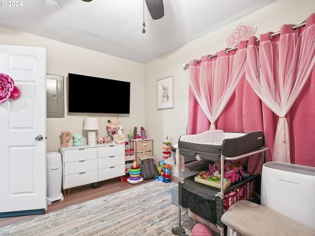 bedroom featuring a textured ceiling, electric panel, dark wood-type flooring, and ceiling fan