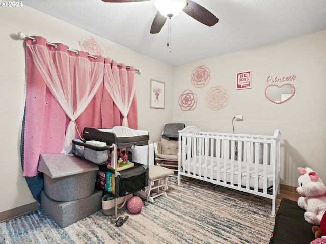 bedroom with ceiling fan and a nursery area