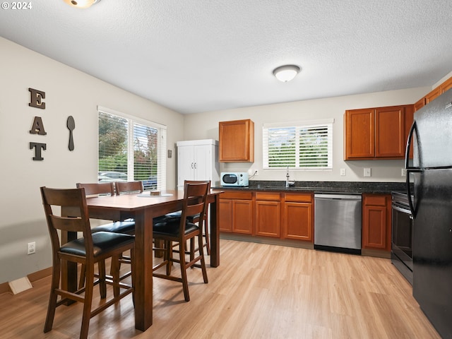 kitchen with sink, stainless steel appliances, a textured ceiling, and light hardwood / wood-style flooring