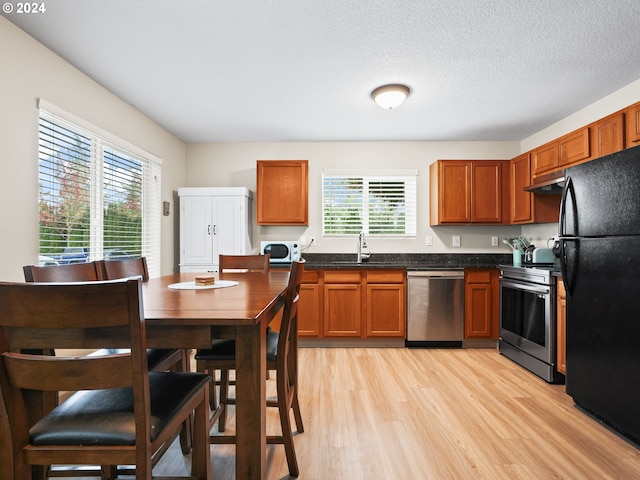 kitchen with sink, appliances with stainless steel finishes, light hardwood / wood-style flooring, and a textured ceiling