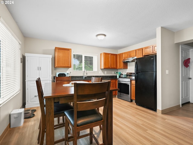 kitchen featuring sink, light wood-type flooring, a textured ceiling, black fridge, and stainless steel electric range