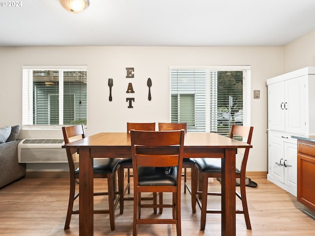 dining area with light hardwood / wood-style floors and a wall mounted AC