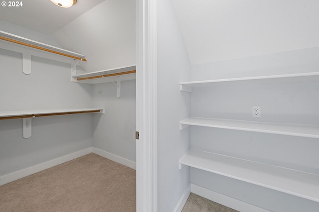 walk in closet with light carpet and lofted ceiling