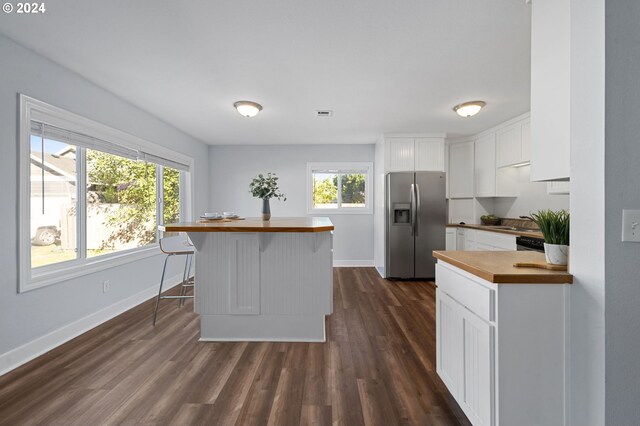 kitchen featuring dark hardwood / wood-style floors, stainless steel fridge, butcher block counters, and white cabinets