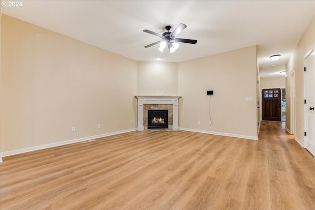 unfurnished living room with a tile fireplace, ceiling fan, and light hardwood / wood-style flooring