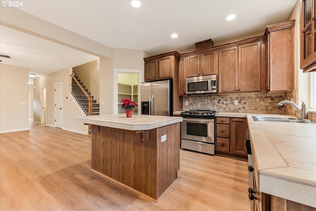 kitchen with tile countertops, a kitchen breakfast bar, a kitchen island, appliances with stainless steel finishes, and light hardwood / wood-style floors