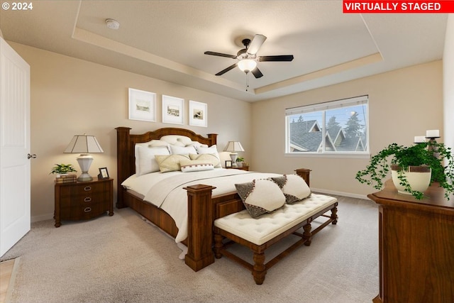 bedroom featuring light carpet, a raised ceiling, and ceiling fan