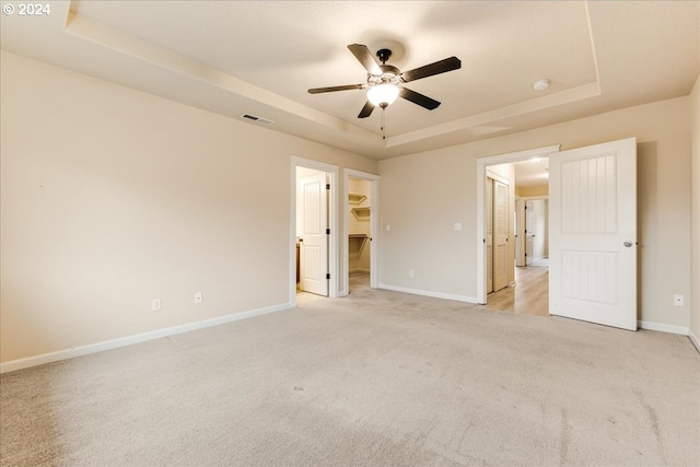 carpeted empty room featuring a tray ceiling and ceiling fan