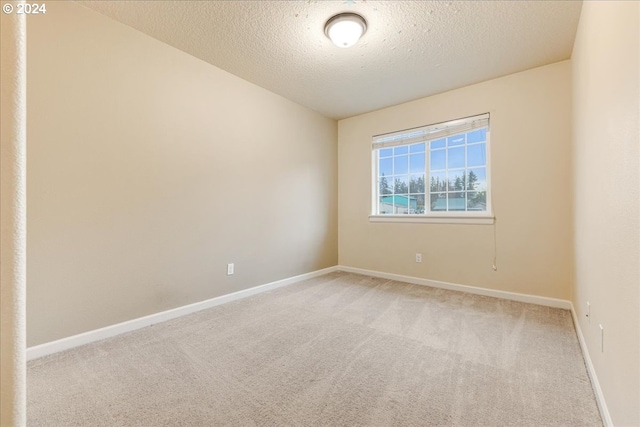 carpeted empty room featuring a textured ceiling