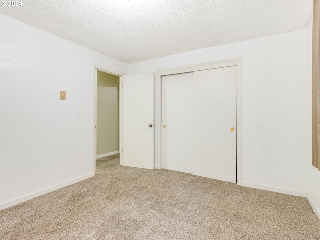 unfurnished bedroom with carpet, a textured ceiling, and a closet