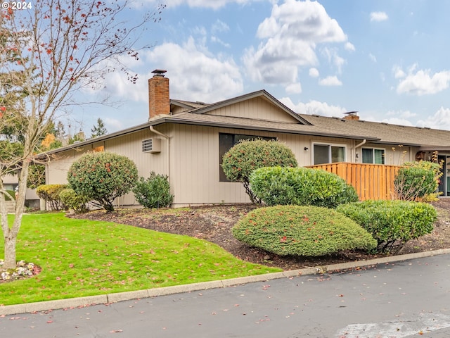 view of home's exterior with a wall mounted air conditioner and a lawn