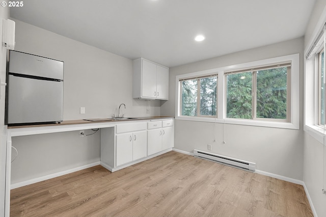 kitchen featuring refrigerator, light hardwood / wood-style flooring, baseboard heating, white cabinets, and sink