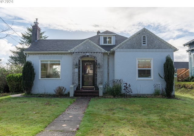 bungalow-style house with a chimney, stucco siding, and a front yard