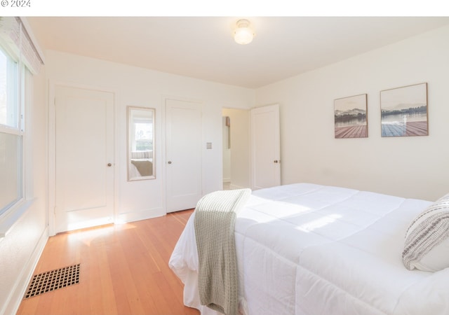 bedroom with light wood-type flooring, baseboards, and visible vents