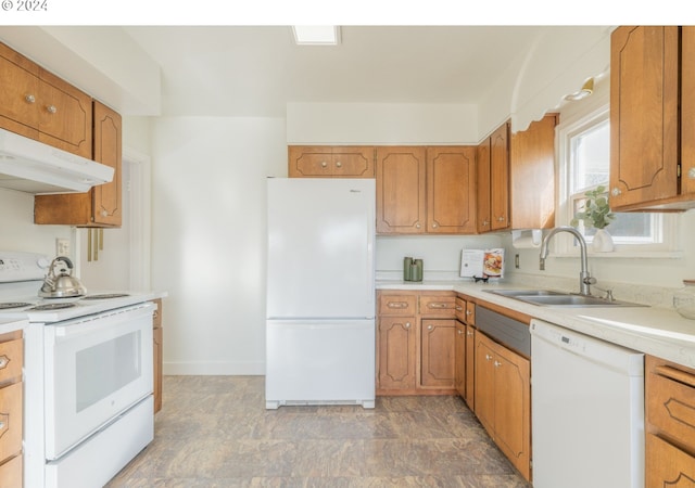 kitchen with brown cabinets, under cabinet range hood, light countertops, a sink, and white appliances