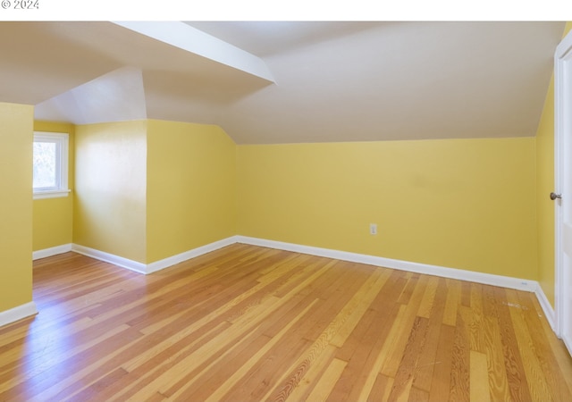 bonus room with light wood-type flooring and lofted ceiling