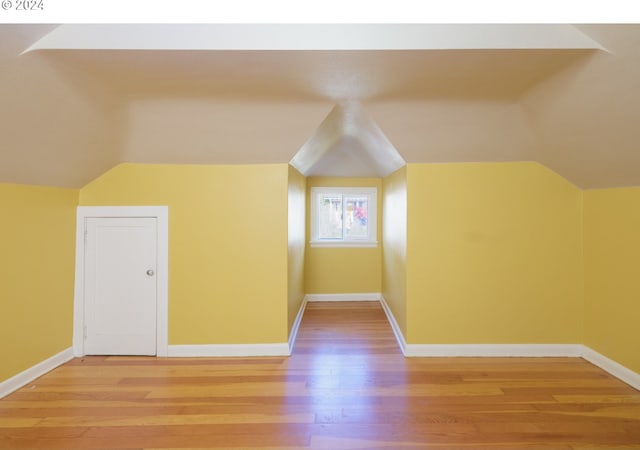 additional living space with lofted ceiling, light wood finished floors, and baseboards