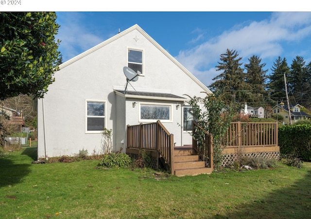 rear view of property with stucco siding, a deck, and a lawn