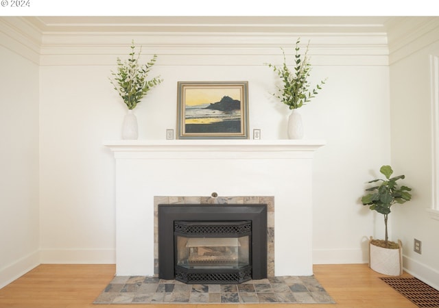 interior details featuring a tiled fireplace, visible vents, baseboards, and wood finished floors