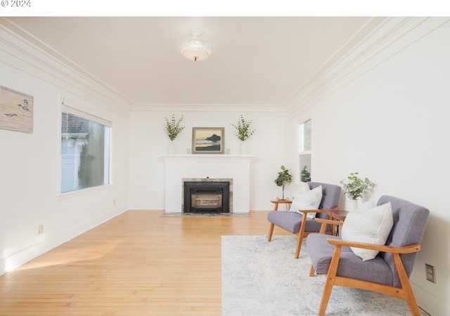 living area with a fireplace with flush hearth, light wood-style flooring, baseboards, and ornamental molding