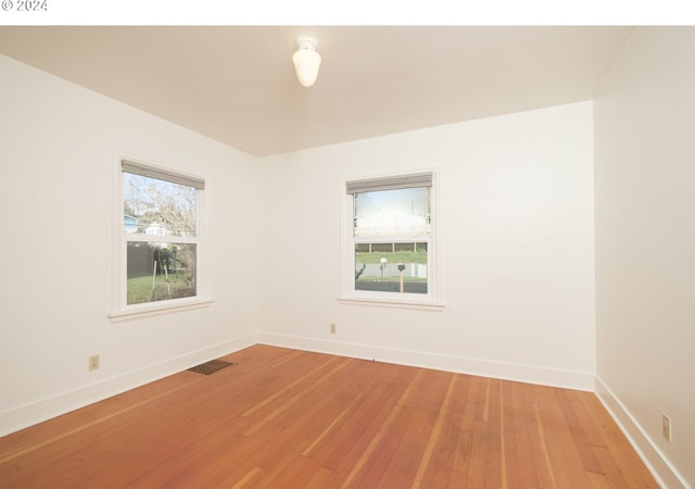 spare room featuring light wood-style flooring, visible vents, and baseboards