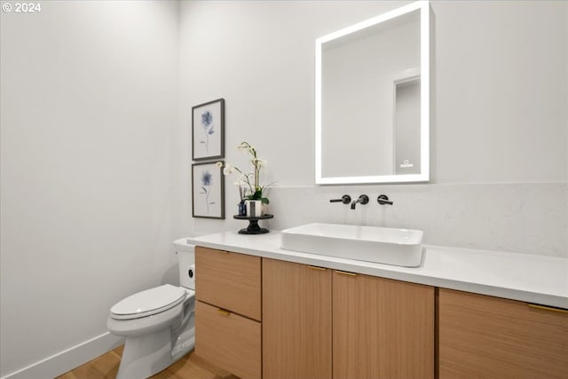 bathroom with toilet, wood-type flooring, and vanity