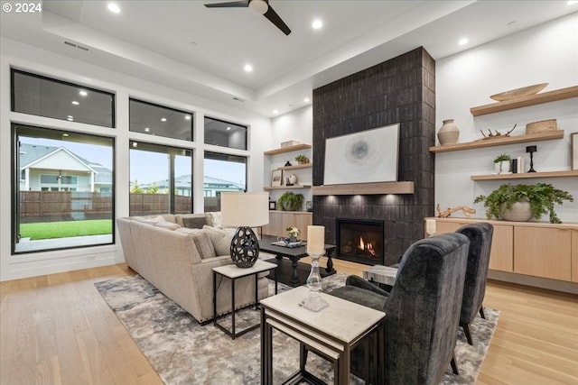 living room featuring a fireplace, ceiling fan, and light hardwood / wood-style flooring