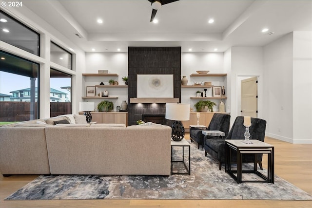 living room with a fireplace, ceiling fan, and light hardwood / wood-style floors