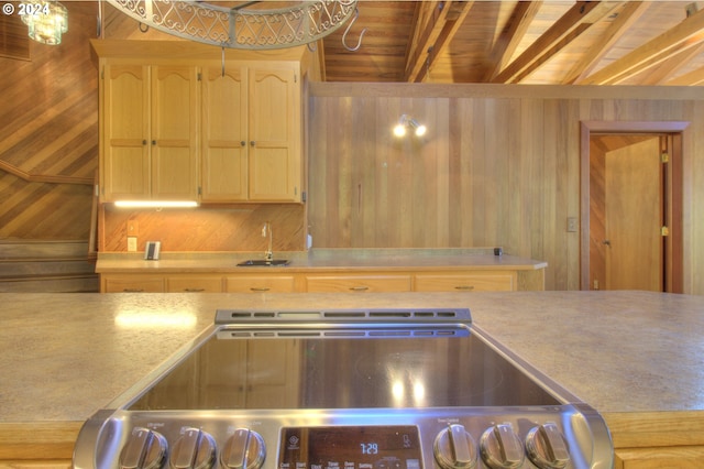 kitchen with sink, lofted ceiling with beams, stove, wooden walls, and wood ceiling