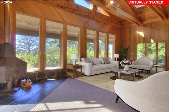 living room featuring beamed ceiling, a wood stove, a wealth of natural light, and wooden ceiling