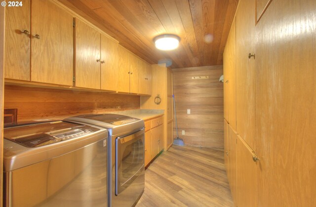 laundry area featuring cabinets, wooden ceiling, light hardwood / wood-style flooring, wood walls, and washer and clothes dryer