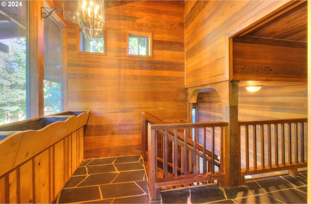 stairs with an inviting chandelier and wooden walls