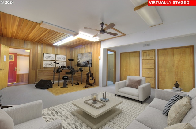 living room featuring wooden walls, ceiling fan, and light colored carpet