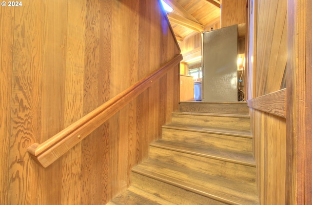 staircase with wood walls and vaulted ceiling