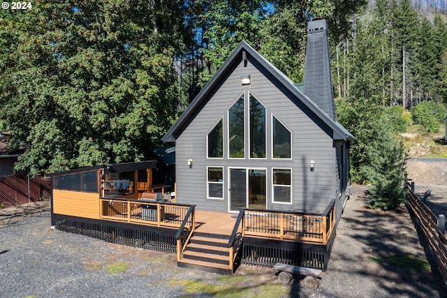 rear view of property featuring a deck, a chimney, and fence