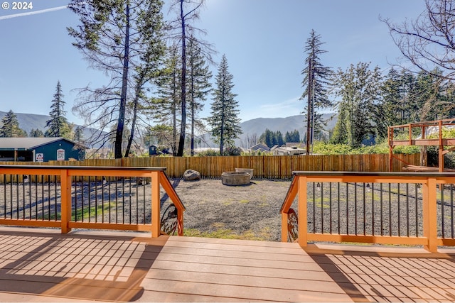 deck featuring a fenced backyard, a mountain view, and a fire pit