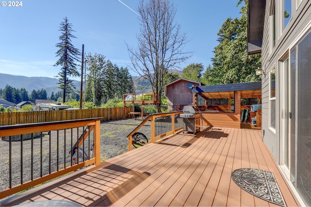 wooden terrace featuring a fenced backyard, a grill, and a mountain view